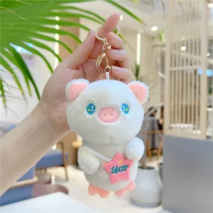 Detail of white plush pig keychain with blue star eyes and gold metal ring hardware