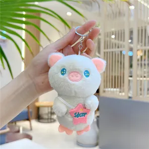 Close-up of cute plush pig keychain with star bag being held in a cozy cafe setting