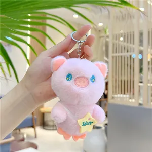 Pink plush pig keychain with star bag detail held in a warm cafe setting
