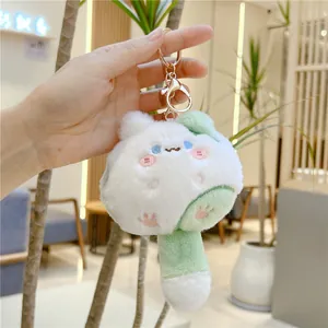Detail of white and green plush cat keychain with golden clasp held in hand
