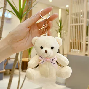 Détail d'un porte-clés ours en peluche crème avec ruban rose Love et fermoir doré