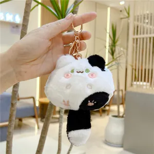 Close-up of plush black and white cat keychain with embroidery and golden clasp
