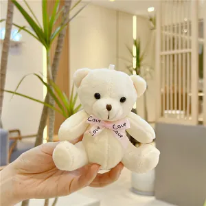 Détail d'un porte-clés ours en peluche crème avec un nœud en soie rose gravé Love