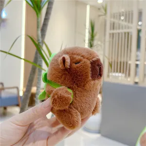 Detail of cute Capybara plush keychain with green dinosaur backpack and soft brown fur
