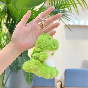 Close-up of a cute green plush dinosaur keychain with golden clip and soft fur texture
