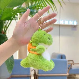 Close-up of a green plush dinosaur keychain featuring a cute orange backpack detail