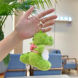 Close-up of green plush dinosaur keychain with pink backpack and metal clasp