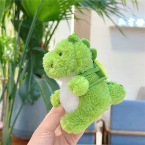 Close-up of a plush green dinosaur keychain with a mini backpack and green lanyard