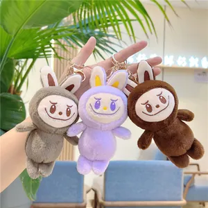Three Labubu plush doll keychains in grey, purple, and brown with gold metal clips
