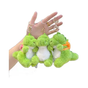 Green plush dinosaur keychain charms with golden metal clasps held in one hand