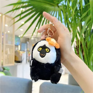 Close-up of a plush white-faced monkey keychain with orange flower and gold metal clip