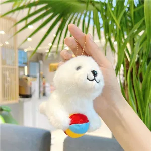 Macro detail of a soft white plush seal keychain featuring a colorful ball and gold chain