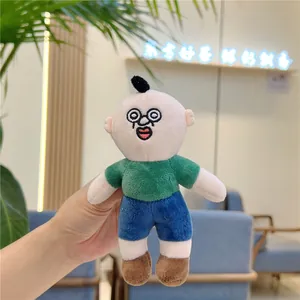 Hand-held close-up of a funny plush doll keychain with glasses and green t-shirt