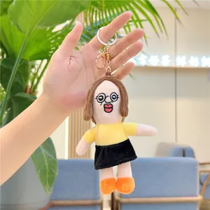 Detailed view of plush human doll keychain featuring yellow T-shirt and round glasses