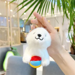 Close-up of a plush white seal pendant holding a colorful ball with golden chain