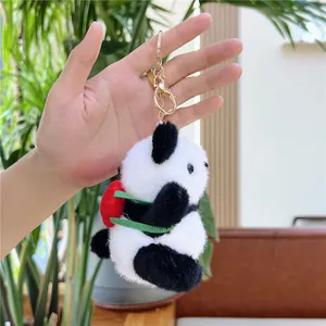 Panda-Plüschanhänger mit roter Tasche und goldenem Schlüsselring in der Hand