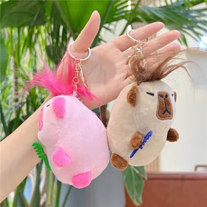Süße Capybara und pinke Plüsch-Schlüsselanhänger mit Mini-Kamm handgehalten präsentiert