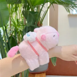 Close-up of a pink plush capybara wristband with a mini white backpack on model's arm