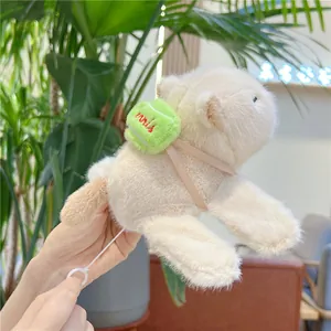 Detail view of capybara plush toy with green mini bag and functional white pull cord