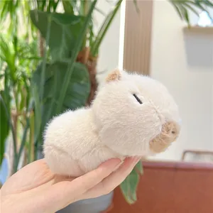 Close-up of a soft plush capybara toy with closed eyes held in hand against greenery