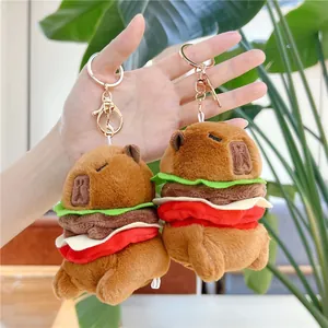 Cute capybara hamburger plush keychain with gold metal clasp on a natural background