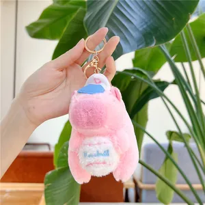 Detailed close-up of a pink capybara plush keychain wearing a blue baseball cap and gold hook