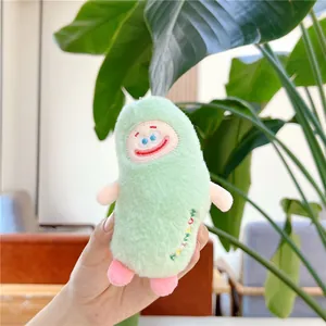 Close-up of cute green plush monster charm with embroidered face and soft fur texture
