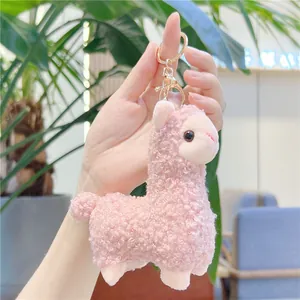 Cute pink alpaca plush keychain with curly fleece and gold clasp in hand-held display