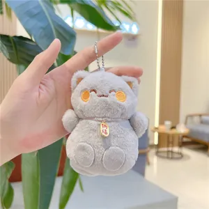 Dettaglio portachiavi gatto in peluche grigio con ciondolo dorato e catenella