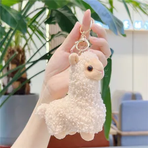 Detail showing plush alpaca keychain with fluffy lamb wool texture and golden lobster clasp