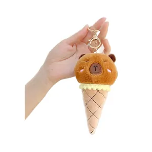 Schattige Capybara ijshoorntje pluche sleutelhanger met gouden ring vastgehouden op wit