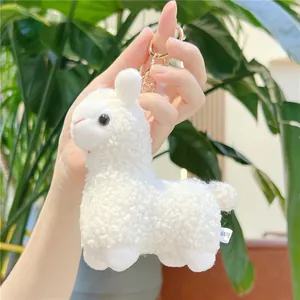 Close-up of white alpaca plush keychain made of fluffy sherpa fabric with gold clasp