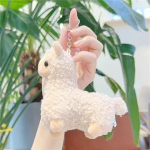 Close-up of a plush white alpaca keychain featuring curly faux fur and silver metal ring