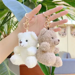 Detail of white and brown curly teddy bear plush charms with gold metal keychains