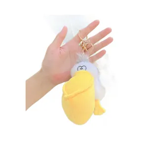 Cute pelican plush keychain with yellow beak and gold lobster clasp hanging on hand
