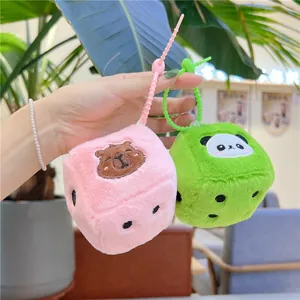 Gros plan de dés en peluche capybara rose et vert avec dragonnes en silicone en main