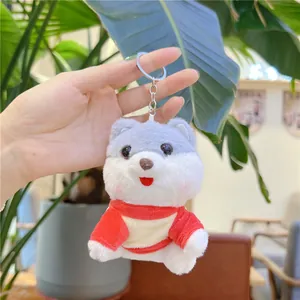 Detail of cute plush dog keychain wearing red sweater held by hand for size context