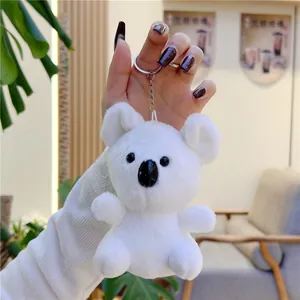 Detailed close-up of a white plush koala keychain with silver metal ring held by a hand