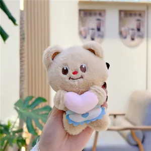 Close-up of cute plush butter bear keychain holding a pink heart with white apron