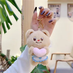 Close-up of plush bear keychain with pink heart and embroidery in hand-held macro view