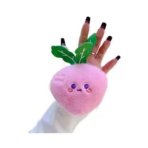 Cute pink radish plush toy keychain with green leaves held by hand on white background
