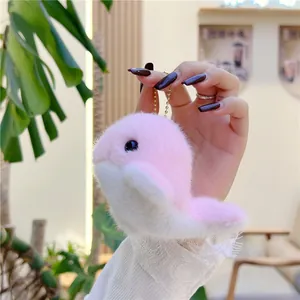 Detailed close-up of a pink plush dolphin keychain held in hand with gold metal chain
