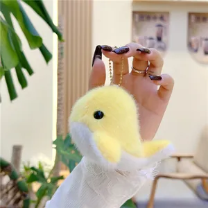 Close-up of a soft yellow and white plush dolphin pendant with a golden keychain hook
