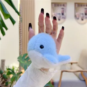 Detail of a fluffy blue dolphin plush keychain with a gold bead chain and soft texture