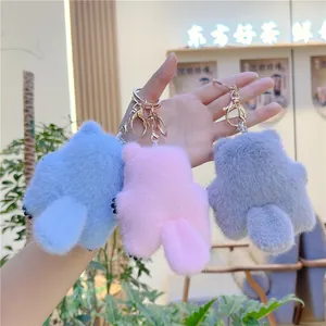 Three plush cat tail keychains in blue, pink, and gray with golden hardware hooks