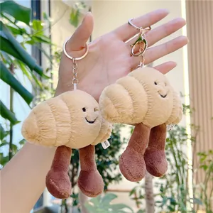 Close-up of cute plush croissant keychain charm with embroidered smiley face and CE tag