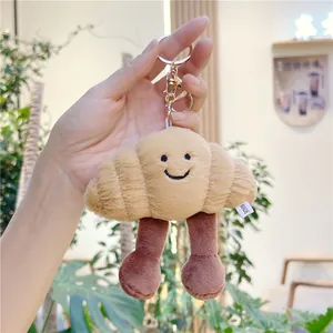 Detail of plush croissant keychain with smiley face embroidery and gold clasp