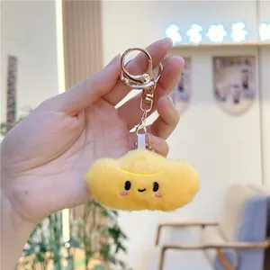 Close-up of yellow plush cloud keychain with embroidered smile and rose gold lobster clasp