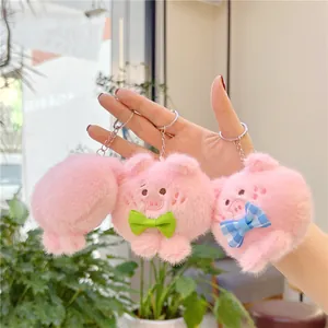 Detailweergave van drie pluizige roze varkensknuffel hangers met gekleurde strikjes