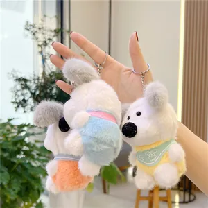 Plush puppy keychains in three colors held by hand in a cozy indoor setting